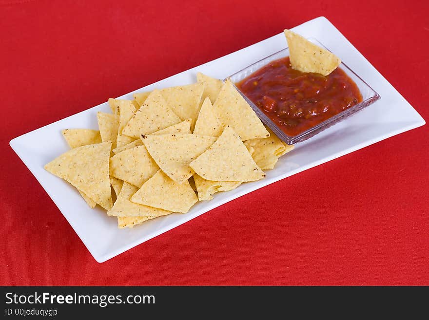 Nachos and salsa sauce on the red background