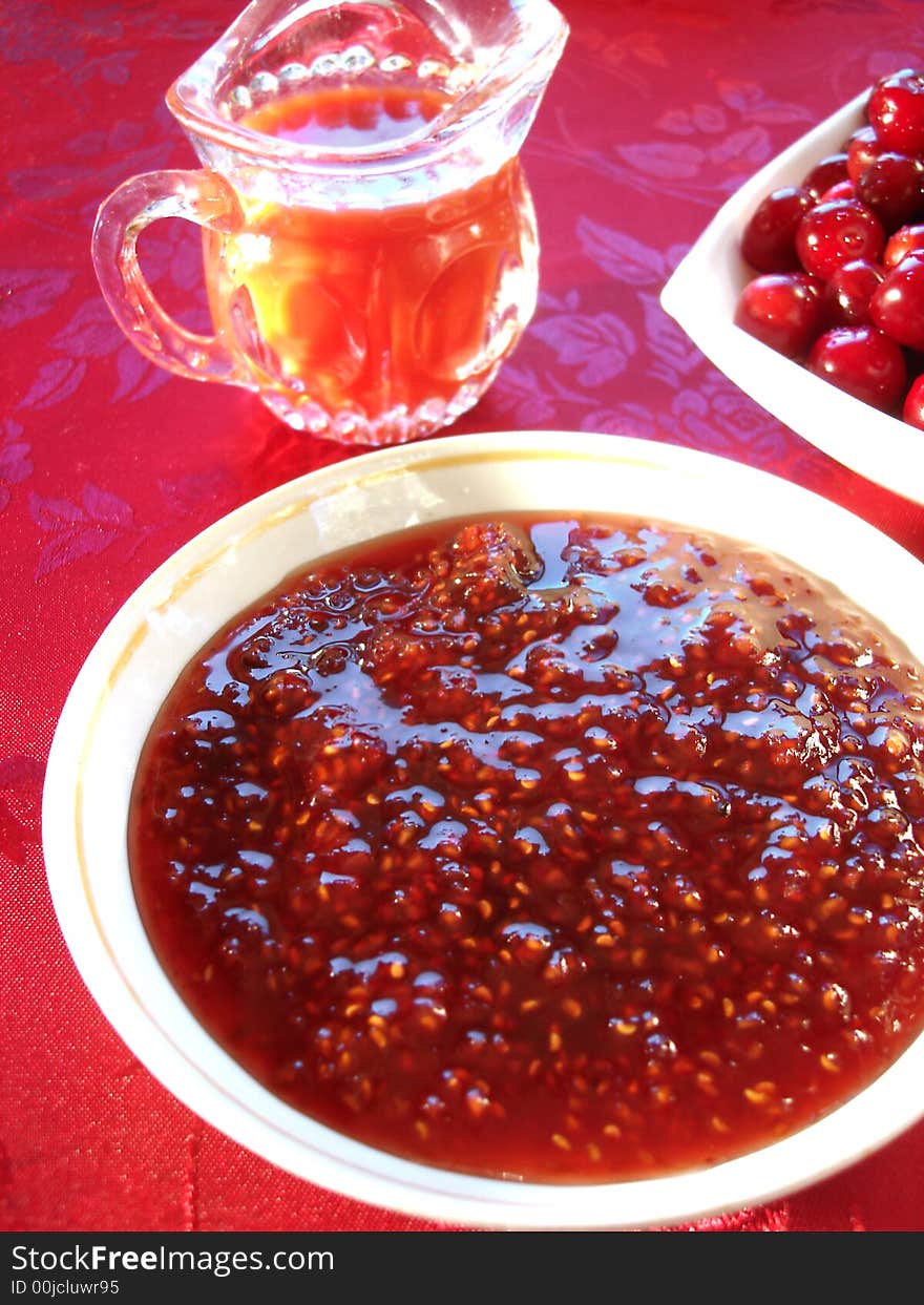 Fresh cherry in bowl, raspberry cooking and beverage on table. Fresh cherry in bowl, raspberry cooking and beverage on table