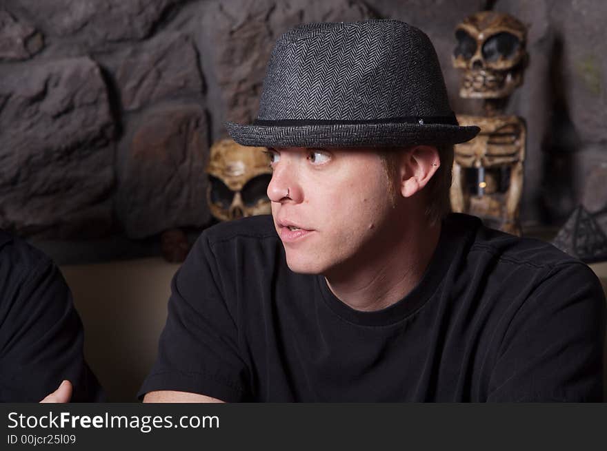 Young man wearing a gray hat with tribal artifacts in background