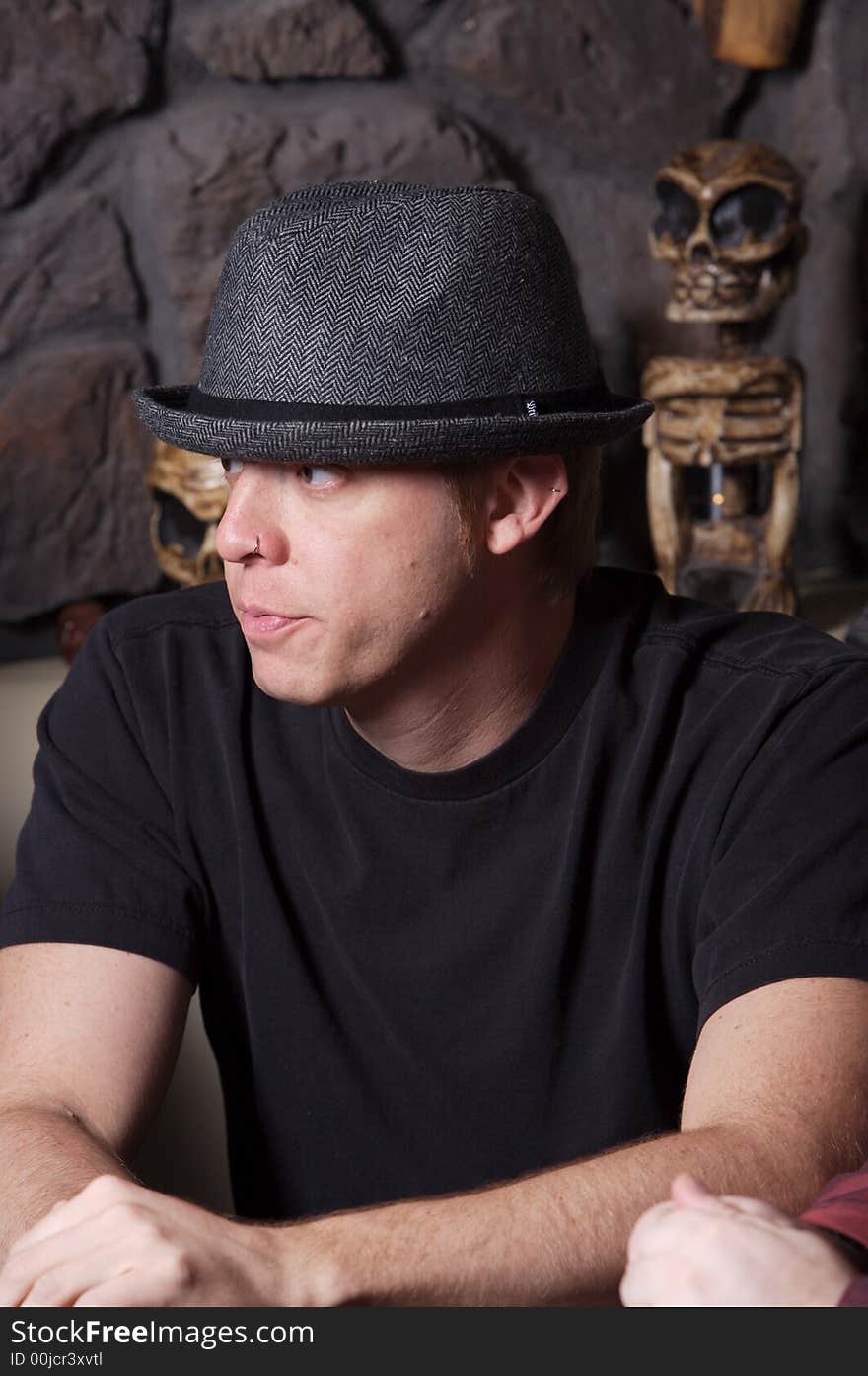 Young man wearing a gray hat with tribal artifacts in background