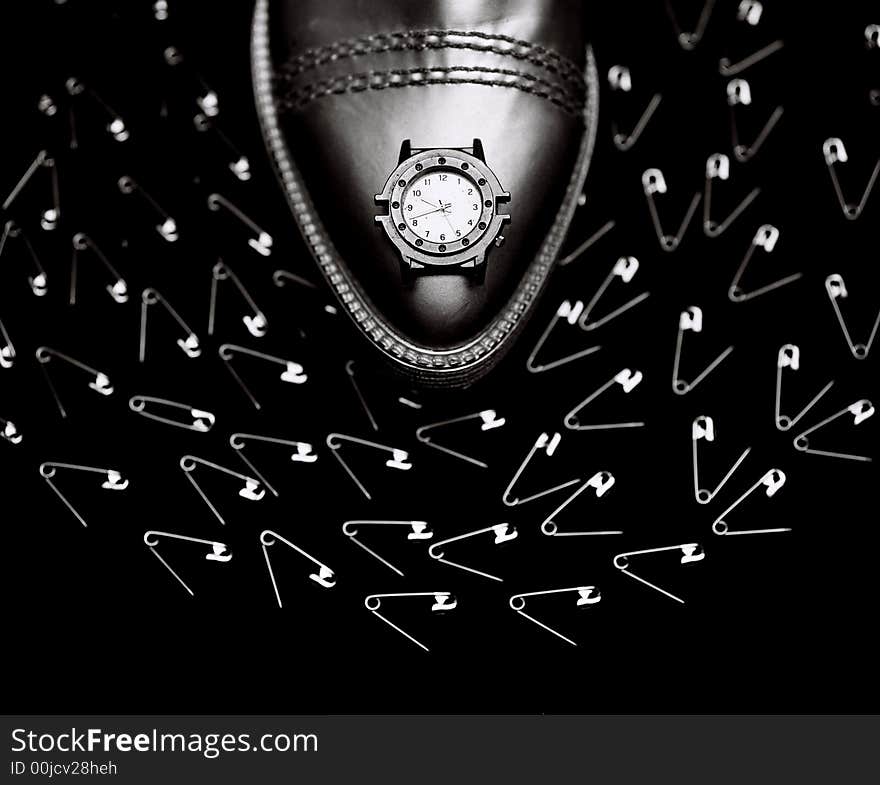 A man\'s watch on a man\'s shoe, representing authority, surrounded by safety pins. A man\'s watch on a man\'s shoe, representing authority, surrounded by safety pins.