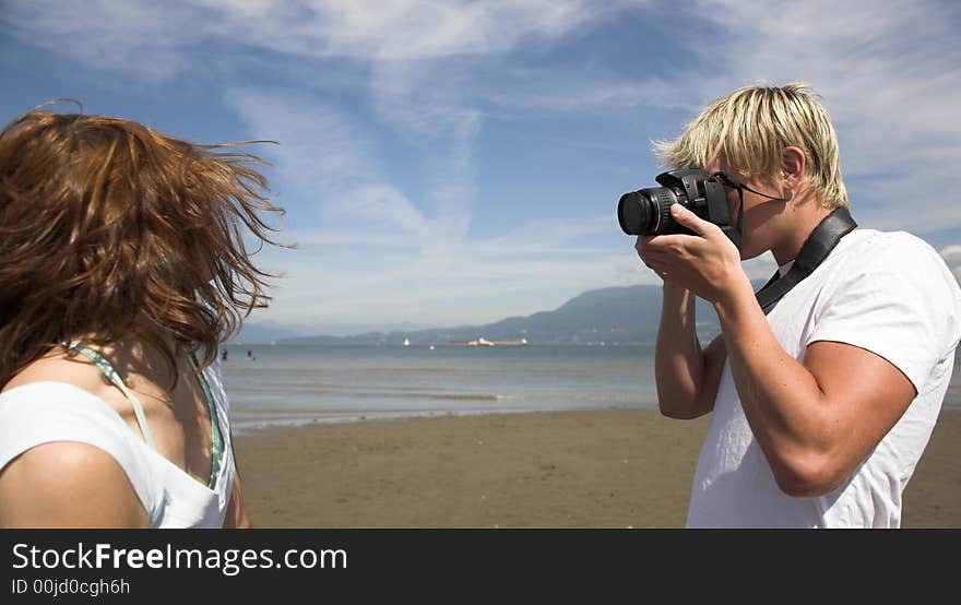 Young couple on the beach with dog in taking pictures