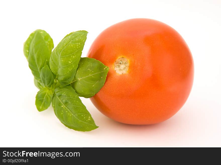 Tomato with basil isolated over white background