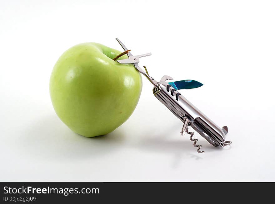 Swiss army knife aimed at an apple. Swiss army knife aimed at an apple