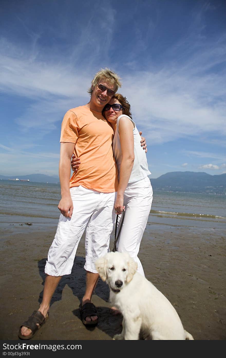 Young couple on the beach with dog in vancouver