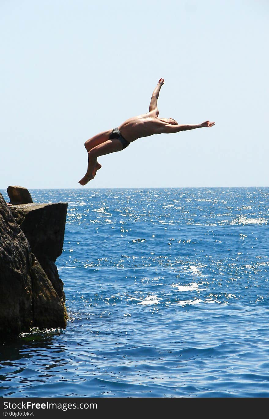 Man making a flip from the rock to the water. Man making a flip from the rock to the water