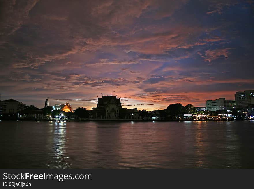 A scenic view of the Chao Praya River in Bangkok, with a temple in the background. A storm shortly before sunset produces a colourful and dramatic sky. A scenic view of the Chao Praya River in Bangkok, with a temple in the background. A storm shortly before sunset produces a colourful and dramatic sky