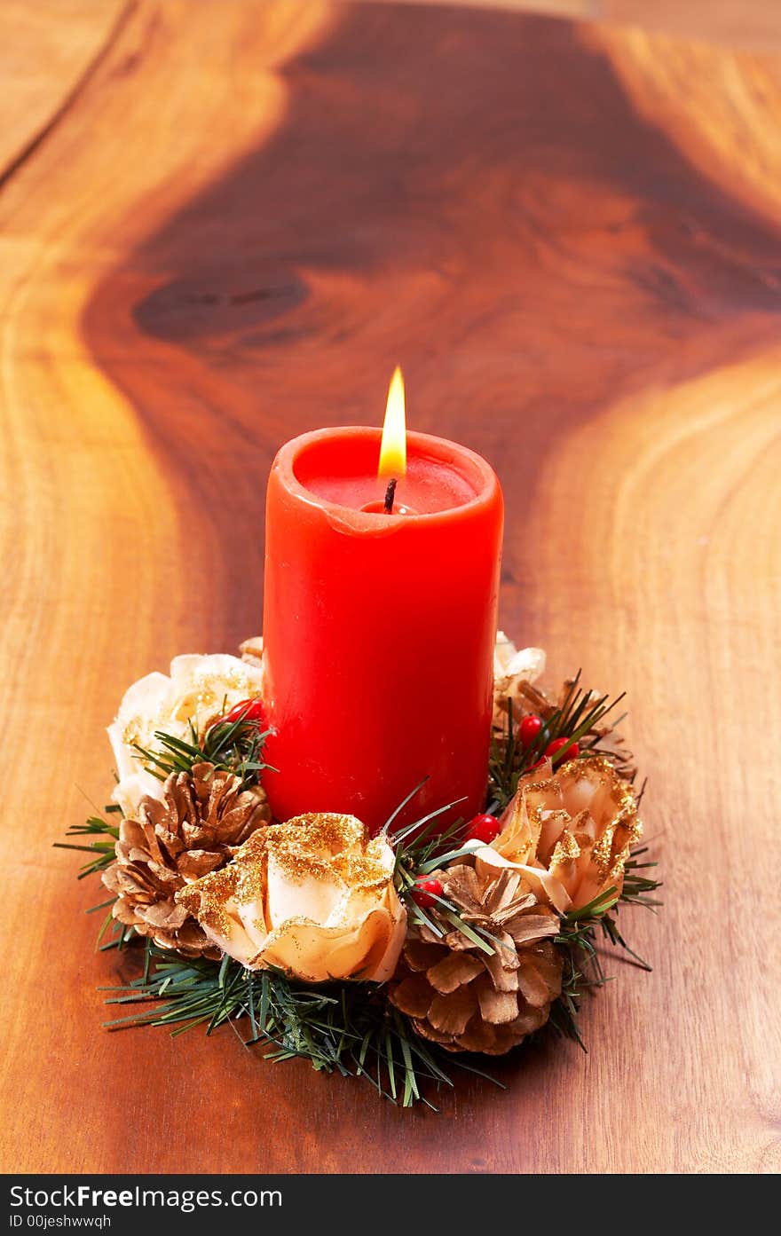 Single red candle in a Christmas decoration on wooden table