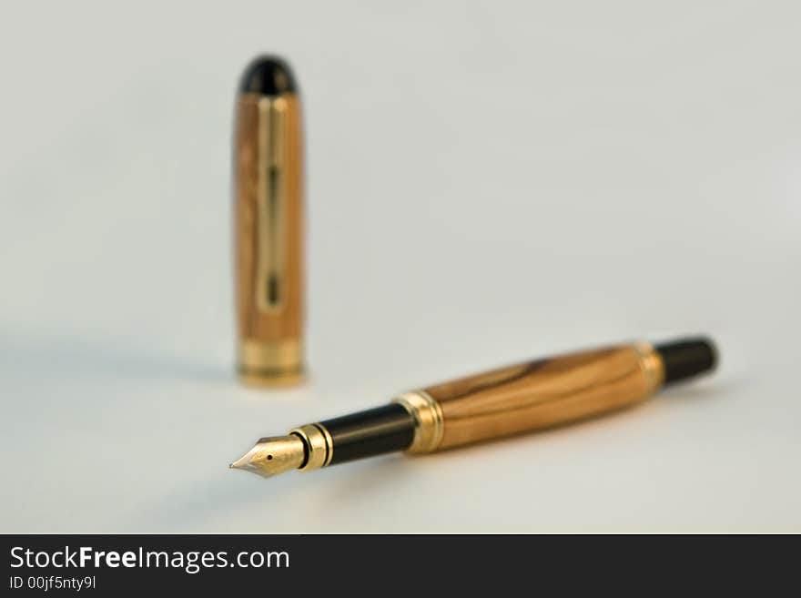 A handmade fountain pen displayed on white with a shallow depth of field (dof). The pen is made from Bethlehem Olive Wood. (The pen was handmade by the photographer in his studio). A handmade fountain pen displayed on white with a shallow depth of field (dof). The pen is made from Bethlehem Olive Wood. (The pen was handmade by the photographer in his studio).