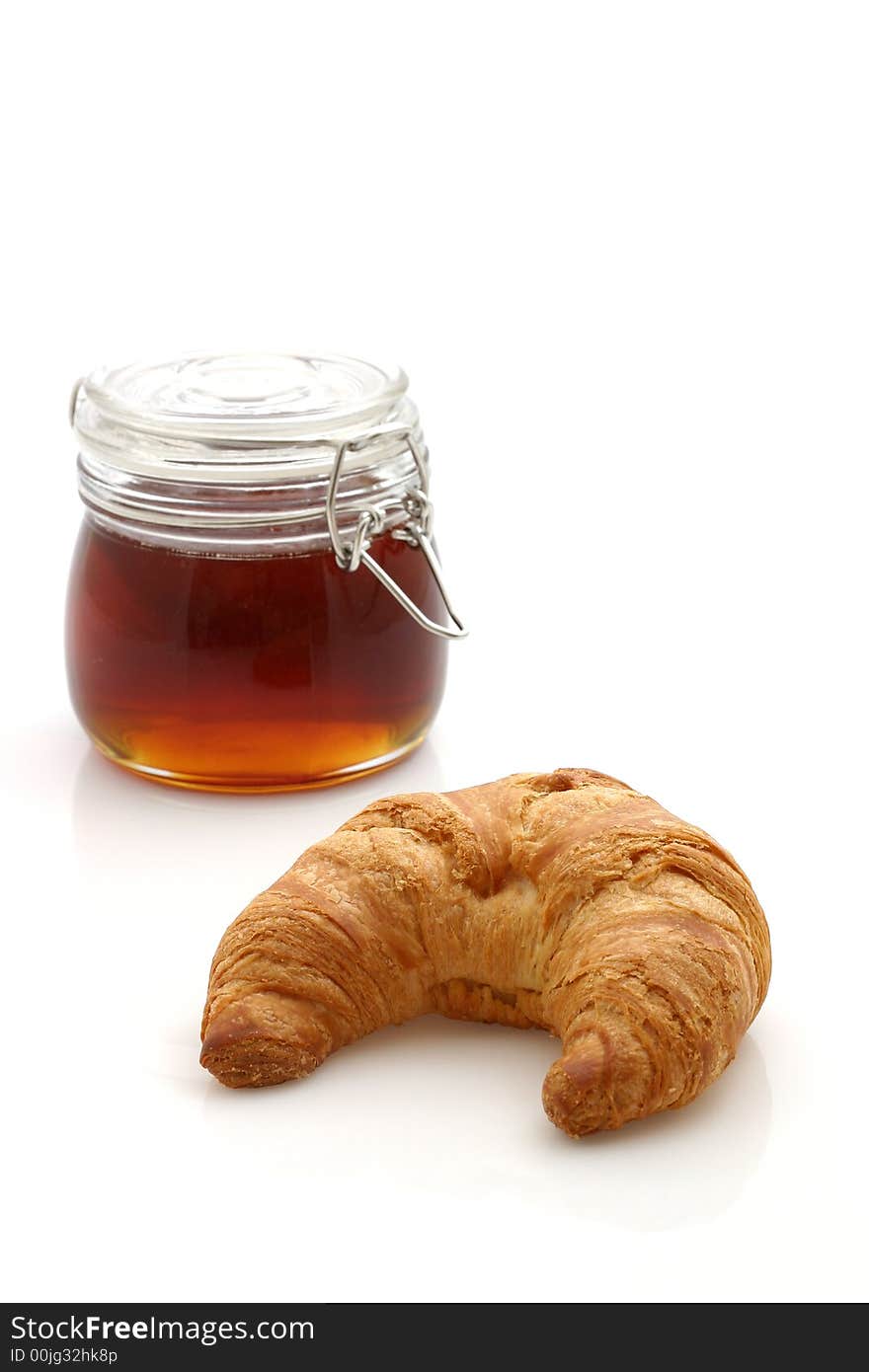 Honey and croissant isolated on white