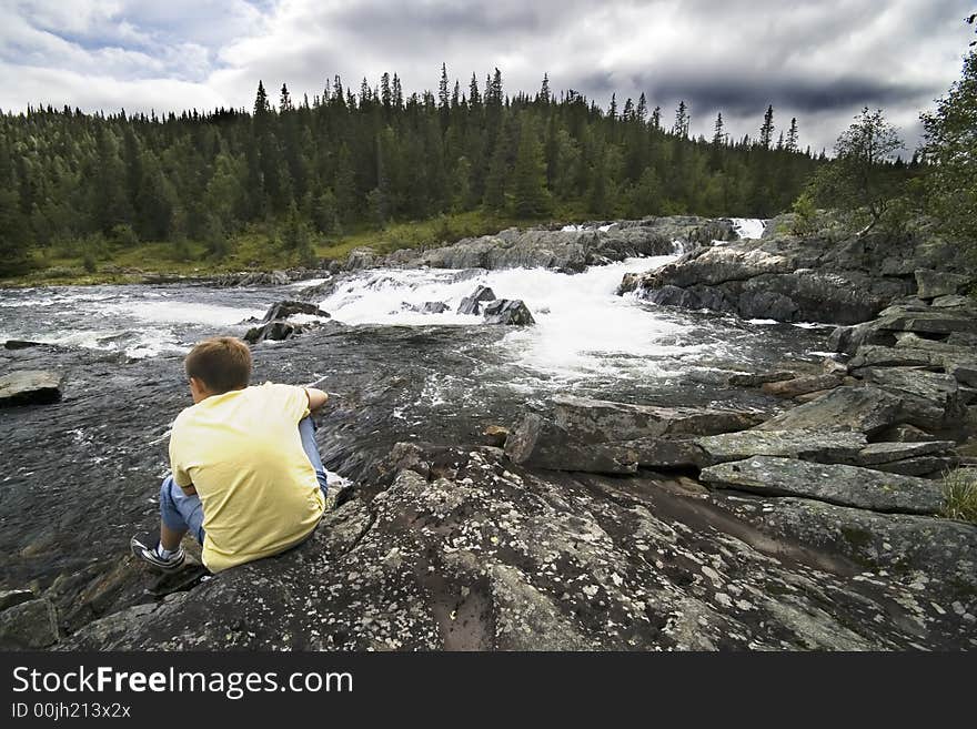 A boy sitting on a bank of a mountain river. Norway. BEAUTY OF NORWAY COLLECTION ». A boy sitting on a bank of a mountain river. Norway. BEAUTY OF NORWAY COLLECTION »