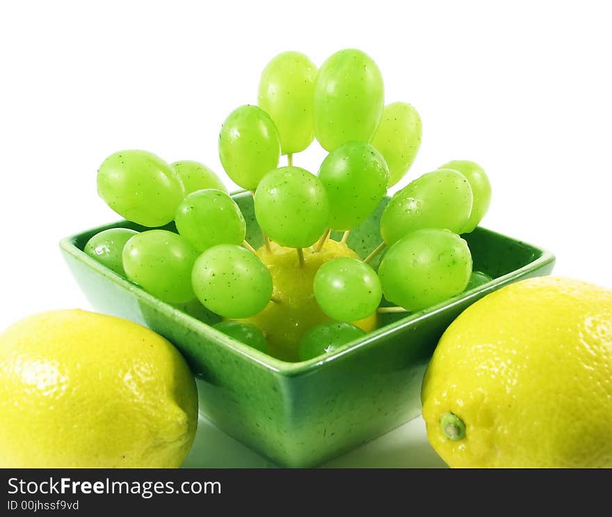 Lemon and grape in green bowl in green bowl on white background. Lemon and grape in green bowl in green bowl on white background