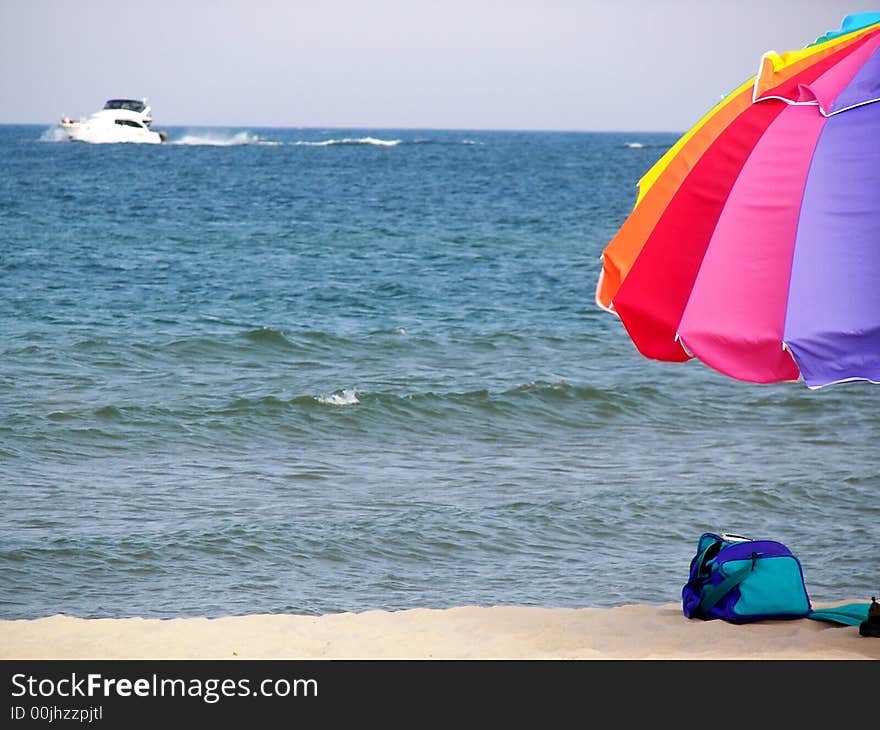 Colorful umbrella on the beach with a power boat on the lake. Colorful umbrella on the beach with a power boat on the lake.