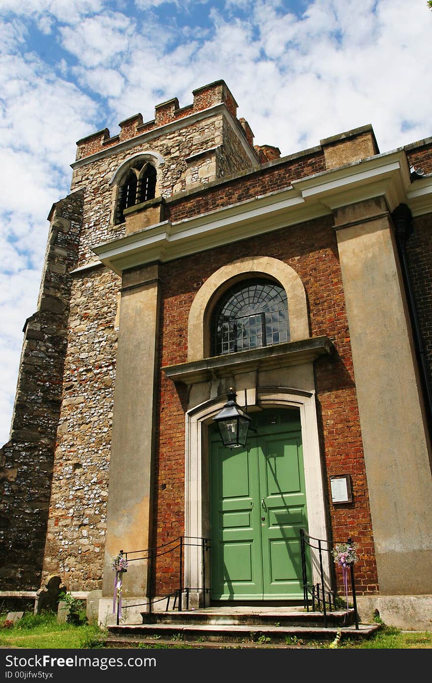 English church door and tower against blue sky and white cloud