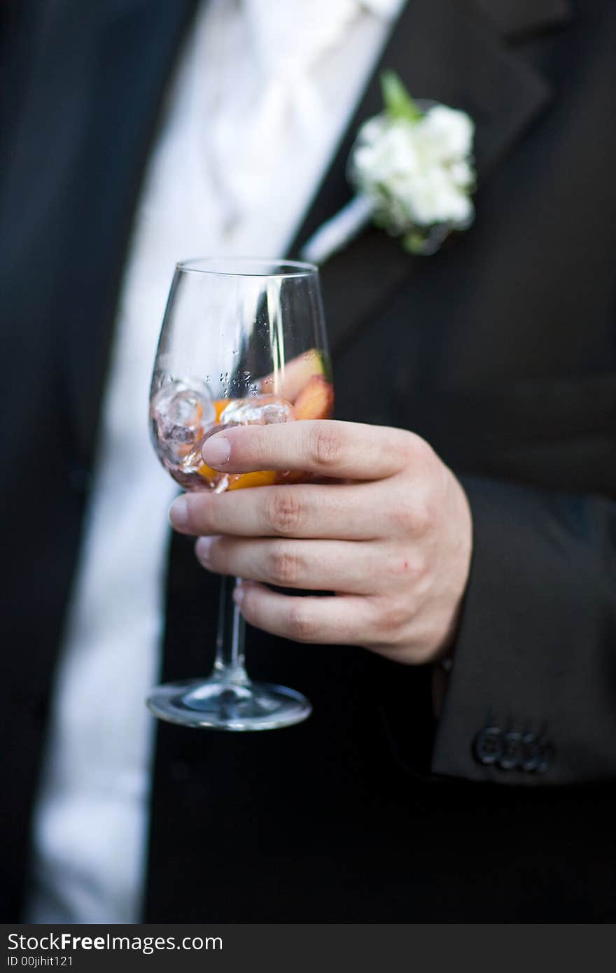 Bridegroom holding a glass of wine-cooler with icecubes. Close-Up. Shallow DOF!