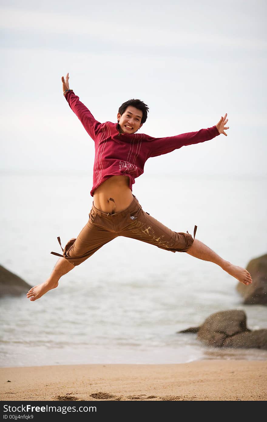 A young man jumping at the beach high and wide. A young man jumping at the beach high and wide