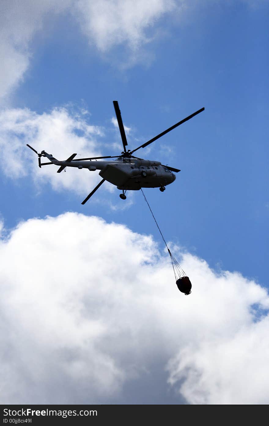 Helicopter with loaded water basket on it's way to douse a fire. Helicopter with loaded water basket on it's way to douse a fire.