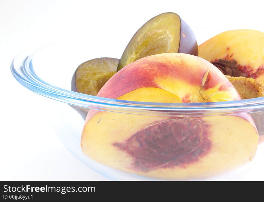 Pieces plums and peaches are in glass vases. Isolated on a white background. Pieces plums and peaches are in glass vases. Isolated on a white background.