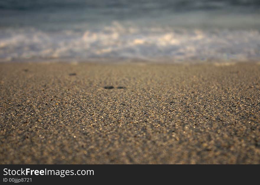 Waves breaking on Nantucket with water droplets spewing out and the focus on the sand in front. Waves breaking on Nantucket with water droplets spewing out and the focus on the sand in front