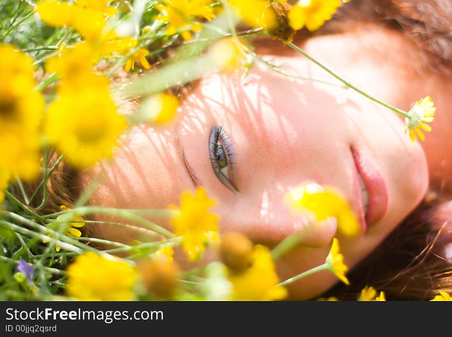 Beautiful girl laying on a field among fresh grass & yellow flowers. Beautiful girl laying on a field among fresh grass & yellow flowers.