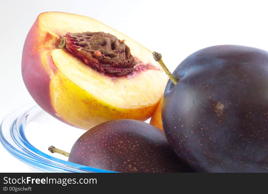 Pieces plums and peaches are in glass vases. Isolated on a white background. Pieces plums and peaches are in glass vases. Isolated on a white background.