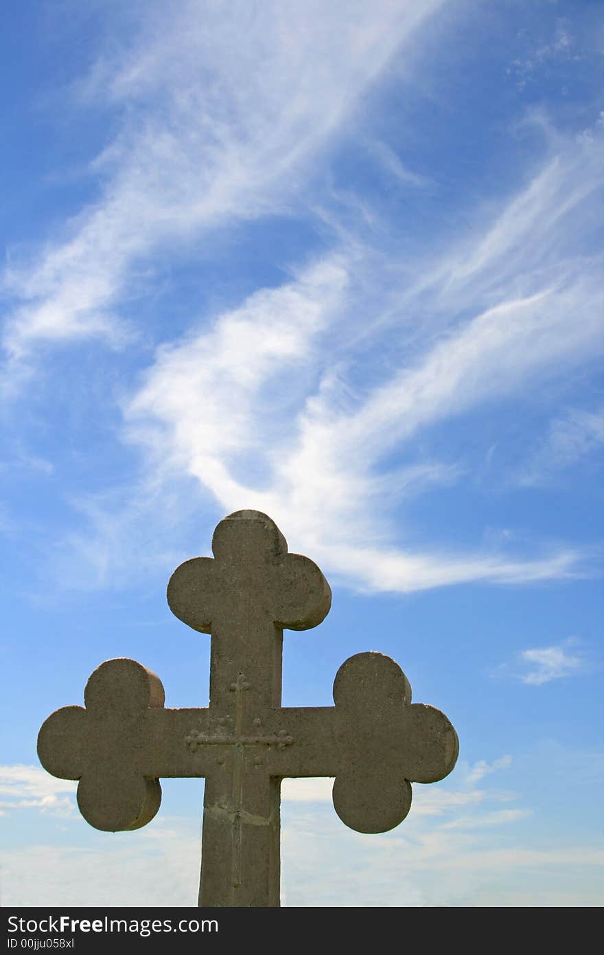 An old concrete tombstone in the shape of a cross.