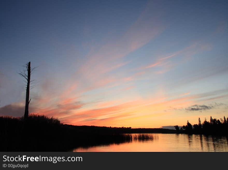 Wide angle sunset over lake with dead tree. Wide angle sunset over lake with dead tree.