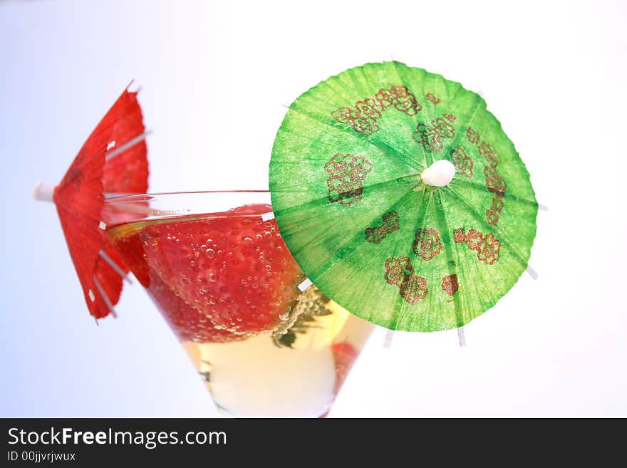 Strawberries in a glass of sparkling apple juice with cocktain umbrellas. Strawberries in a glass of sparkling apple juice with cocktain umbrellas