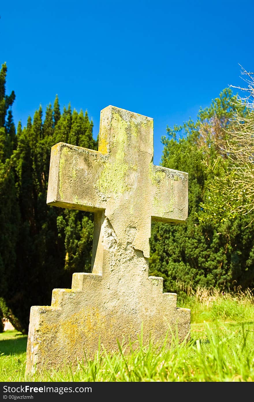 Weathered cross-form gravestone against sky. Weathered cross-form gravestone against sky