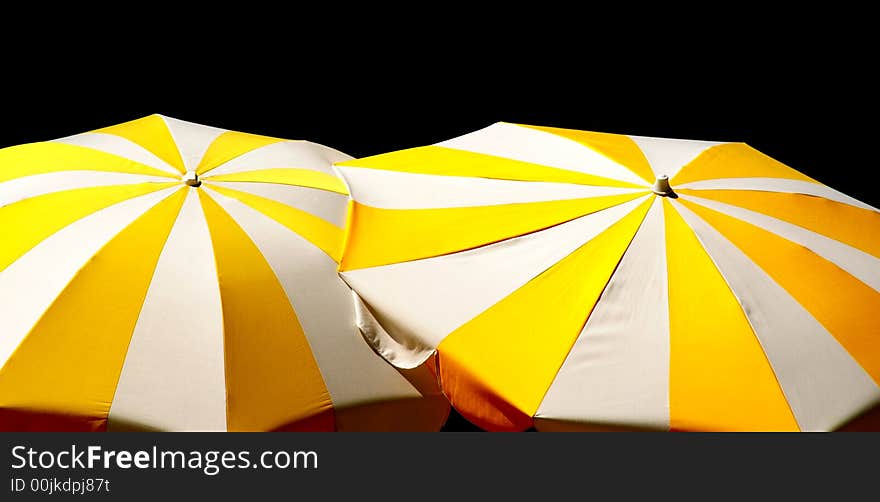 Two yellow-white parasols on black background. Two yellow-white parasols on black background