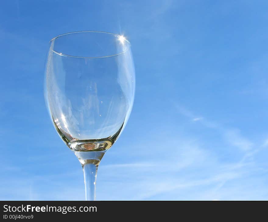 Empty wineglass on sky background