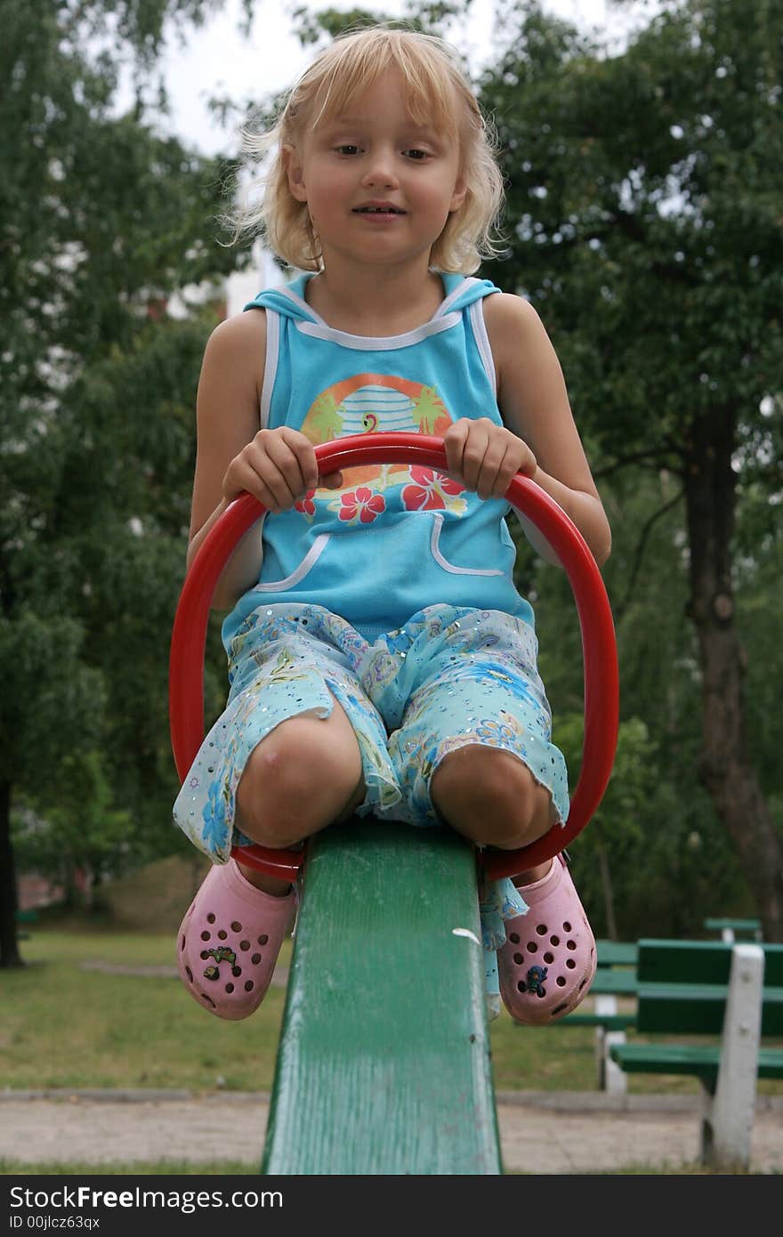 Pretty childhood girl swaying on the balance swing