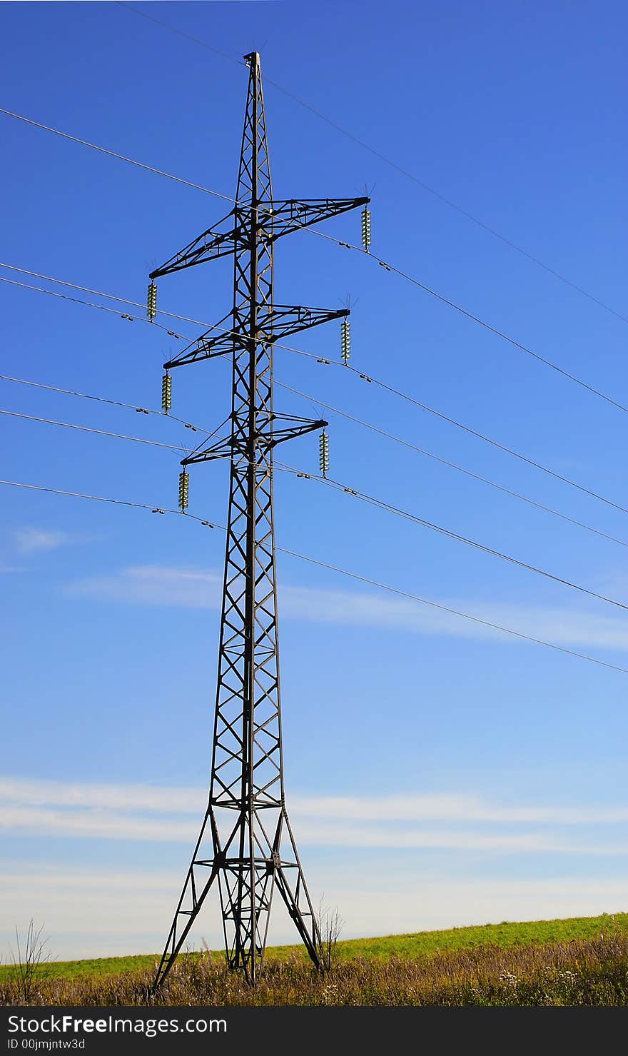 A support of a high-voltage electric line on a background of a bright dark blue autumn field. A support of a high-voltage electric line on a background of a bright dark blue autumn field.