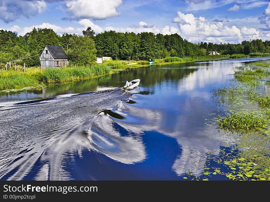 Motor boat on the river with reflection of the cloudy sky at the countryside. Motor boat on the river with reflection of the cloudy sky at the countryside