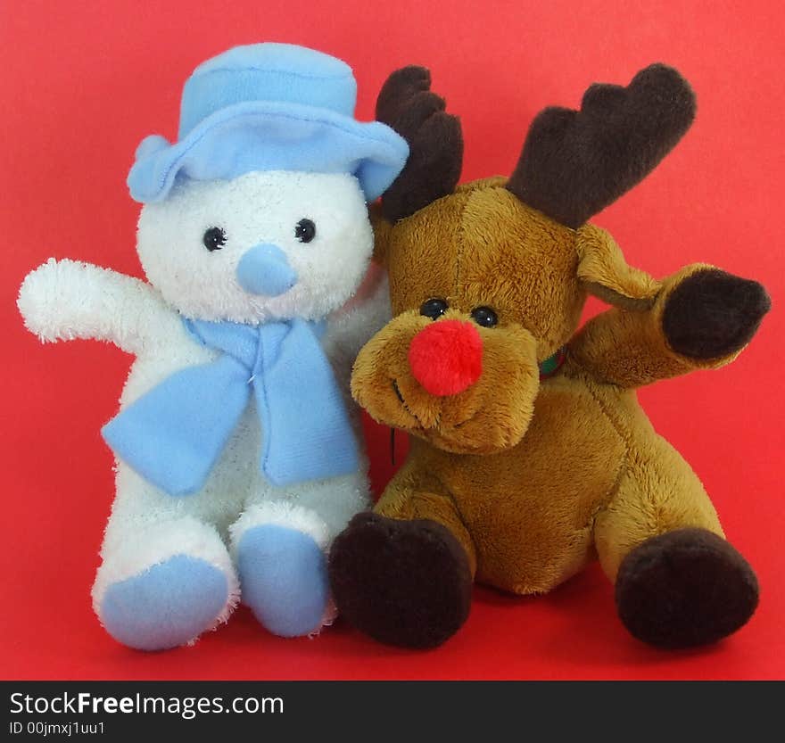 A cute plush snowman and reindeer on a red background. A cute plush snowman and reindeer on a red background.