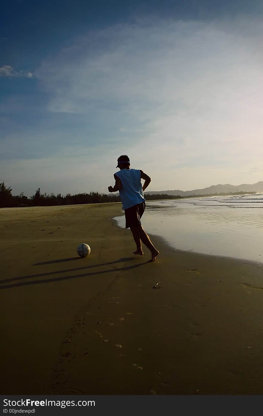 A guy kicking a soccer ball around in the beach. A guy kicking a soccer ball around in the beach