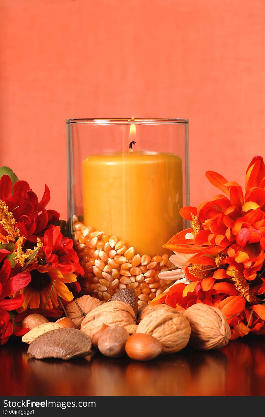 Candle in an autumn setting surrounded with nuts and flowers. Candle in an autumn setting surrounded with nuts and flowers