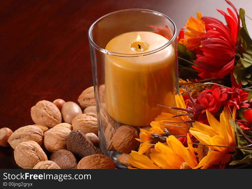 Candle in an autumn setting with nuts and flowers. Candle in an autumn setting with nuts and flowers