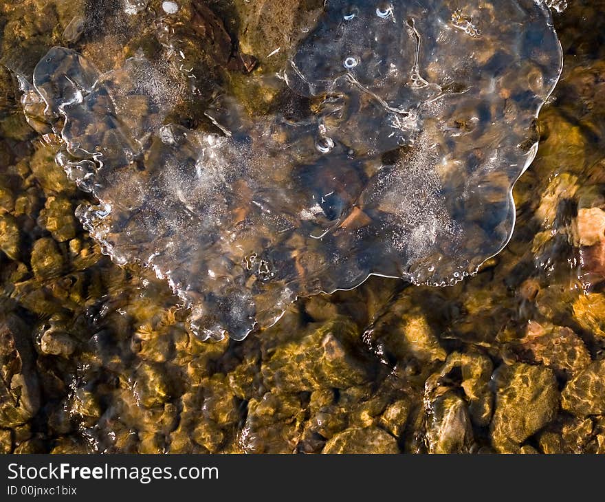 Winter frozen forest stream background with flowing water and ice over it. Winter frozen forest stream background with flowing water and ice over it