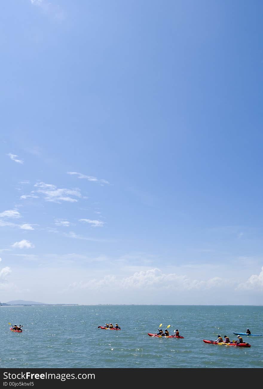 People canoeing as part of their training in the open sea under a clear blue sky. People canoeing as part of their training in the open sea under a clear blue sky.