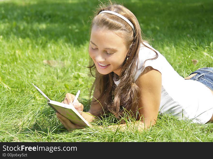 Beautiful young girl making notes in her notebook