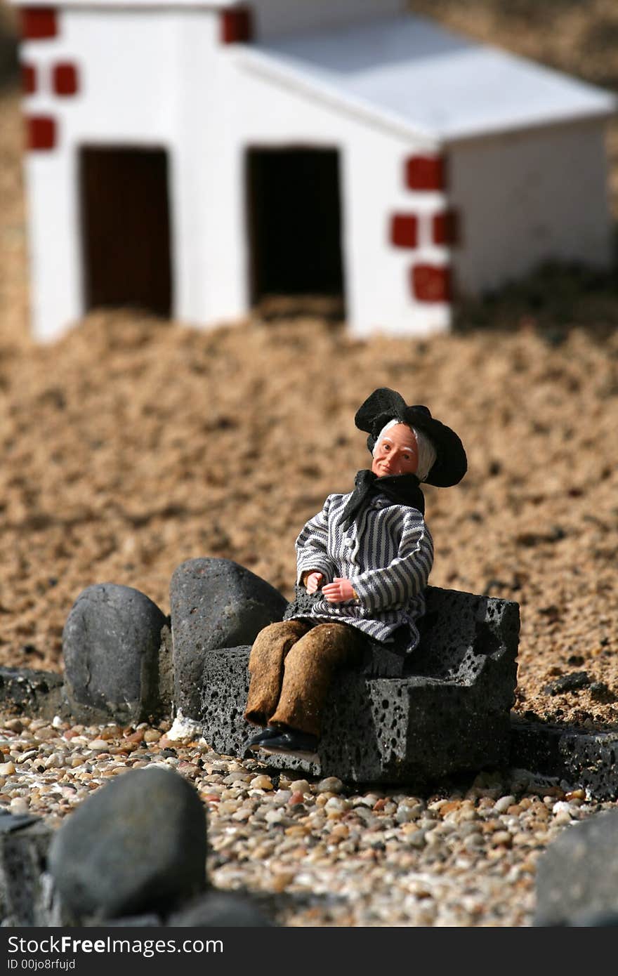 Miniature woman seated in front of white house. Miniature woman seated in front of white house