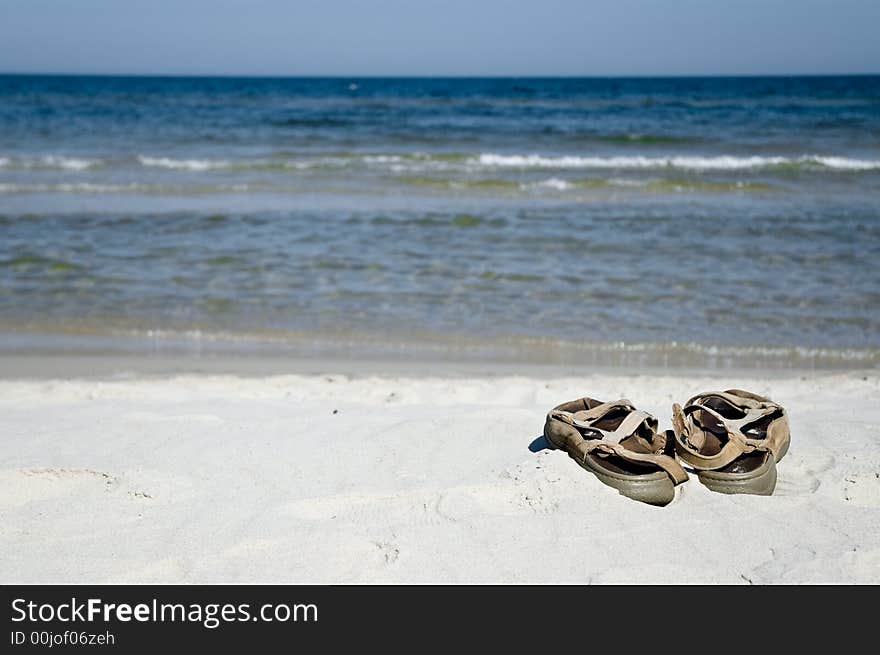 Pair of sandals on the beach, ocean in background