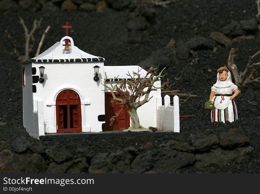 Miniature spanish woman in front of white church. Miniature spanish woman in front of white church