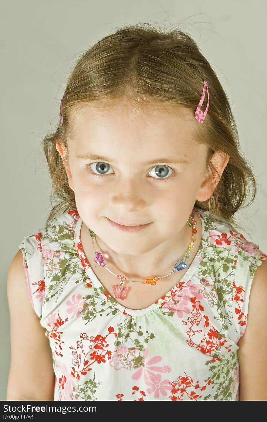 Smiling young girl in a print dress.  Plain background, head and shoulders portrait.