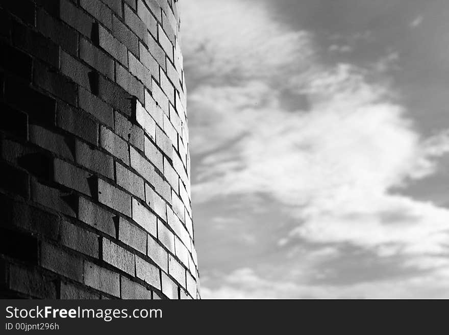 Hard curved brick wall against soft clouds. Hard curved brick wall against soft clouds