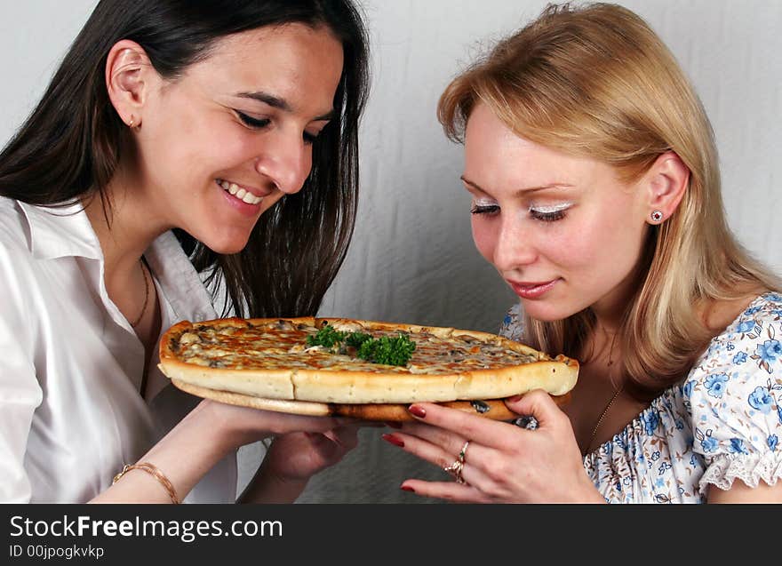 Two girls consider an appetizing pizza. Two girls consider an appetizing pizza