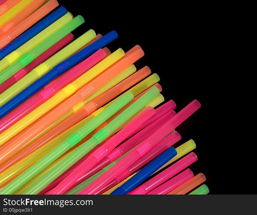 Colorful straws, angled in from the bottom left corner of the photo, stand out dramatically against the black background.