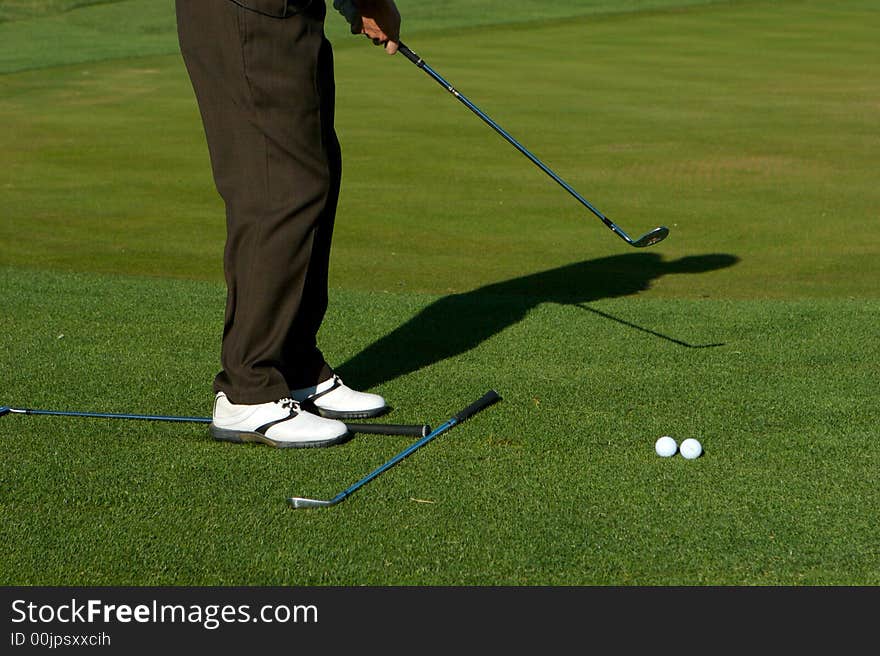 Golfer taking practice swings and aligning on a golf course. Golfer taking practice swings and aligning on a golf course