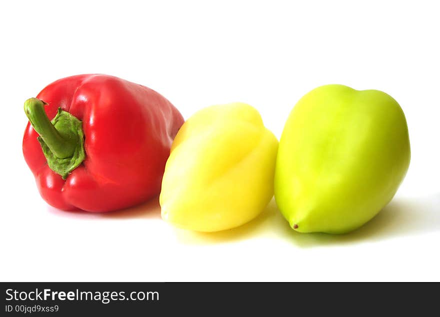 Red, yellow and green peppers over white background